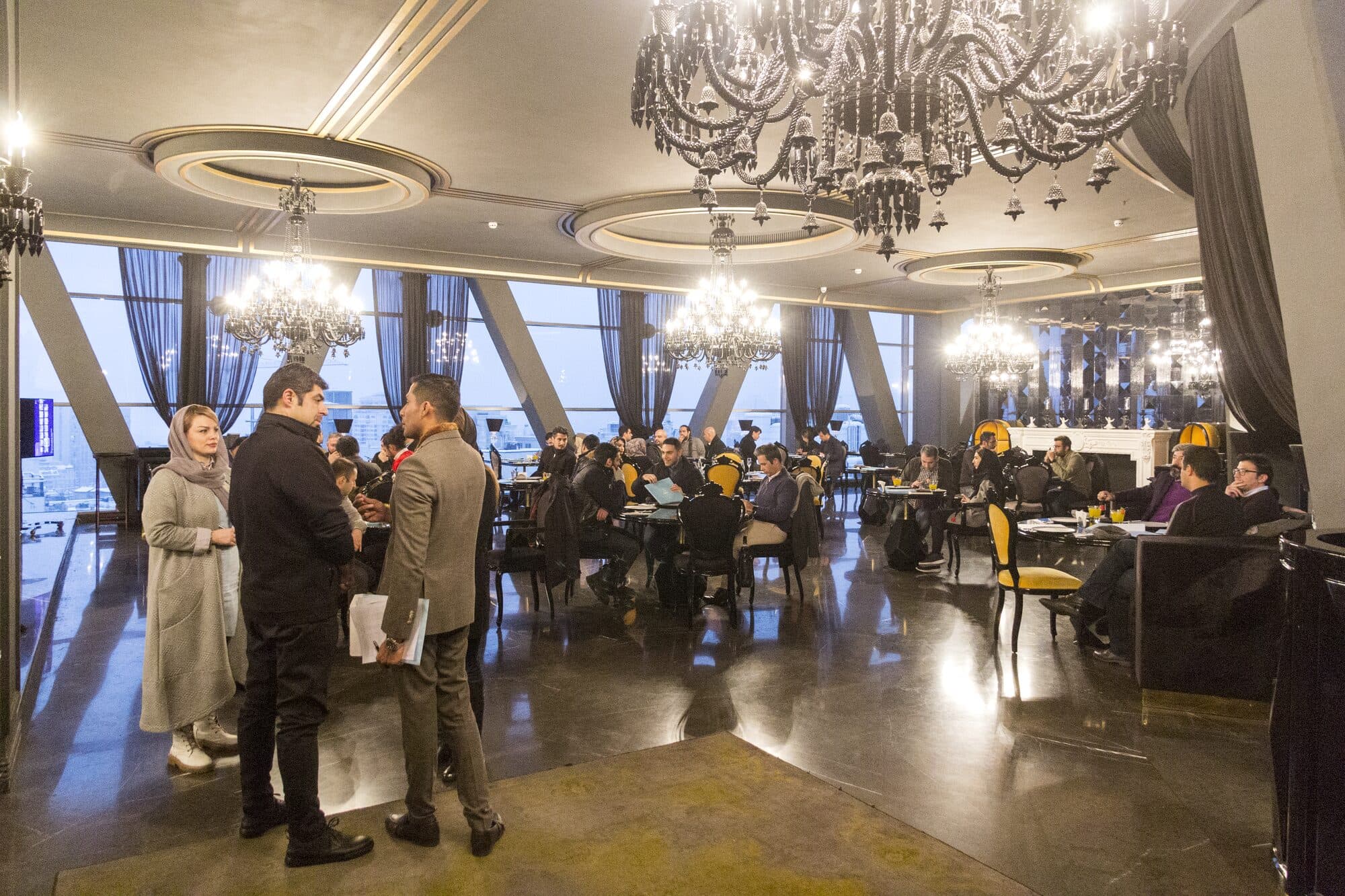 The room at Ava Center before the presentation: chandeliers, the city through the glass, and tables of building-industry guests already in conversation